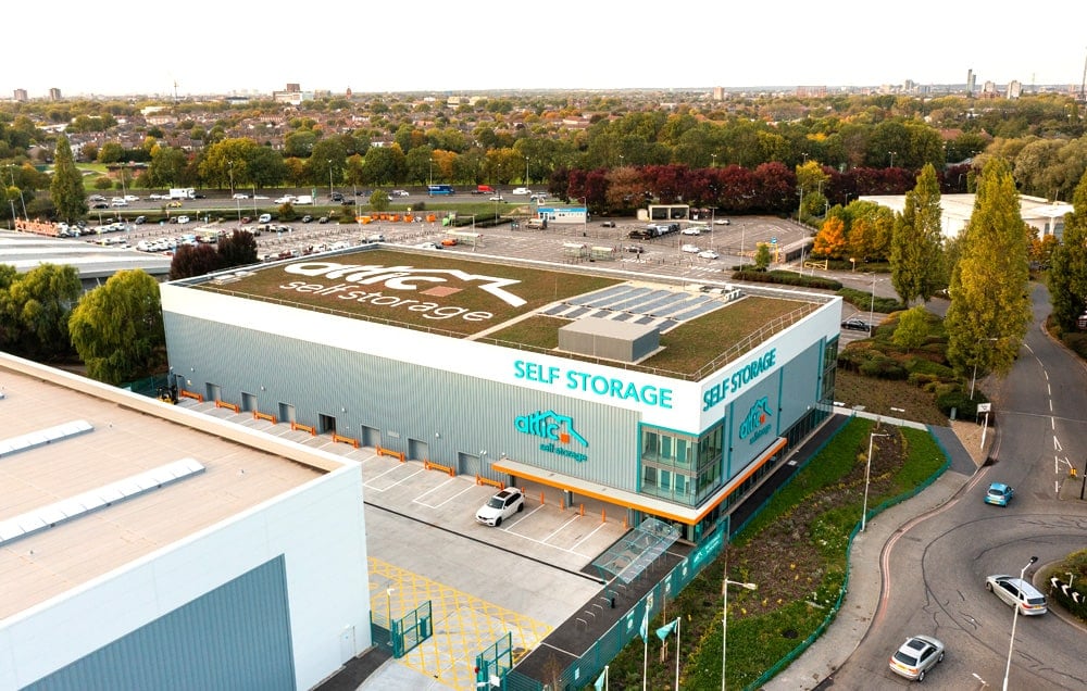 An aerial view of a self-storage facility with rows of metal storage units and a green roof.