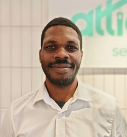 A man of colour in a white formal shirt smiles at the camera. Attic Self Storage logo is on the background.